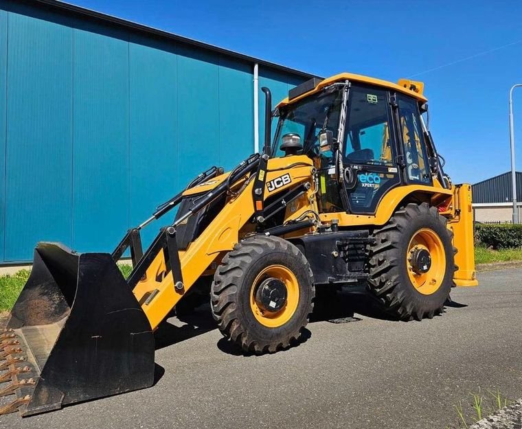 New JCB 3DX ecoXPERT backhoe loader parked in front of a blue warehouse